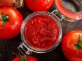 Frische Tomaten um ein Glas mit selbstgemachtem Tomatenmark. Perfekt für Saucen und mehr!