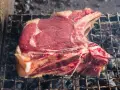 Bistecca alla fiorentina cruda su griglia, pronta per la cottura. Il tempo cottura fiorentina è fondamentale per una perfetta riuscita.