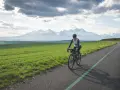 Kobieta na rowerze pokonuje malowniczą trasę z widokiem na ośnieżone Tatry. To wyzwanie: rowerem dookoła Tatr w jeden dzień!