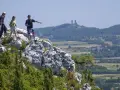 Trzech turystów na skalistym szczycie, wskazując na ruiny zamku w oddali. Piękne krajobrazy gór Kielc.