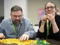 Zwei Personen bauen mit bunten Legosteinen, während sie an einem software architecture summit teilnehmen.