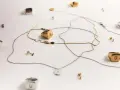 Joyas con letras, como limpiar la plata para que brillen. Anillos y collares dorados y plateados sobre fondo blanco.