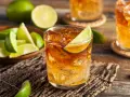 Idealny drink z rumem i lodem, ozdobiony plasterkiem limonki. Obok miseczka z kawałkami limonki, sugerująca, z czym pić rum.