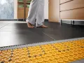 Piedi nudi su un pavimento piastrellato, con un sistema di riscaldamento ad aria calda visibile sotto.