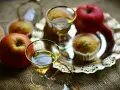 Zwei Gläser mit goldenem Schnaps, Äpfel und Muffins auf einem Silbertablett. Perfekt für den Genuss von selbstgemachtem Kartoffelschnaps.