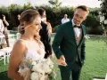 Para Młoda trzyma bukiet, a Pan Młody w zielonym garniturze uśmiecha się do niej. To piękny moment podczas urlopu okolicznościowego ślub.