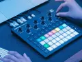 Ręce tworzą muzykę na Novation Circuit Rhythm, z podłączonym laptopem i kablami.
