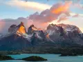 Wspaniała wycieczka do Chile! Słońce oświetla skaliste szczyty Torres del Paine, odbijając się w turkusowym jeziorze.