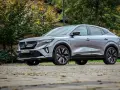 Nowy Renault Rafale, elegancki SUV coupe, prezentuje się na tle jesiennej zieleni i ceglanej ściany.