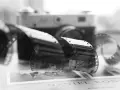 Analogowa fotografia: zwoje kliszy filmowej przed aparatem, na tle książki z napisem "DANIEL KONI".