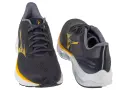 Dwa buty do biegania Mizuno w kolorze grafitowym z żółtymi akcentami. Mizuno to znana firma sportowa.
