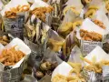 Una variedad de fritura de pescado, incluyendo camarones, boquerones y calamares, servidos en conos de papel.