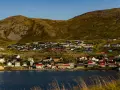 Kolorowe domy nad fiordem, w tle górzysty krajobraz. Nordcamp Norwegia, malownicza wioska rybacka.