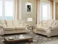 Elegante soggiorno con divani chiari, un tavolino e una lampada. Il tessuto sembra il miglior tessuto per divani antimacchia, ideale per una casa raffinata.