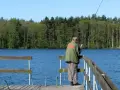 Wędkarz na pomoście nad spokojnym zalewem Koronowskim, w tle las.
