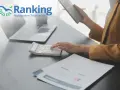 Dłoń kobiety używającej kalkulatora na biurku z laptopem i dokumentami.
