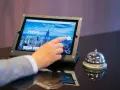 Dłoń dotyka ekranu tabletu z napisem "Welcome to UpScale". Czy można zarezerwować hotel w wieku 17 lat? Obok dzwonek hotelowy.