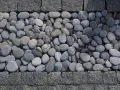 Gładkie, szare kamienie tworzą naturalną dekorację w ogrodzie, otoczone granitową kostką.