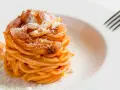 Un piatto di spaghetti alla amatriciana ricetta, conditi con guanciale croccante e pecorino grattugiato, pronti per essere gustati.