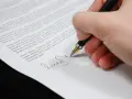 Podpisanie umowy o służebność przesyłu. Dłoń z piórem składa podpis na dokumencie prawnym.