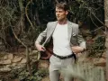 Elegancki mężczyzna w jasnej marynarce i spodniach, z białą koszulką. Idealna stylizacja, jak ubrać się na wesele jako gość, by wyglądać stylowo.