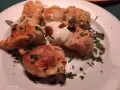 Pierogi, un piatto tipico polacco, serviti su un piatto bianco con panna acida e prezzemolo tritato.
