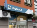 Logo i szyld salonu okien i drzwi "BUDVAR" z napisem "OKNA DRZWI ROLETY".