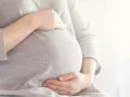 Brzuszek w 6 miesiącu ciąży, delikatnie otulony dłońmi.
