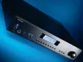 Czarny wzmacniacz Rotel A12 MKII z niebieskim podświetleniem, wyświetlaczem Bluetooth i pokrętłem głośności.