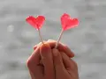 Dos piruletas rojas en forma de corazón, sostenidas por manos entrelazadas, como un símbolo de amor y una **venus carta astral**.