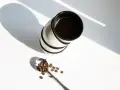Stos kawy w filiżankach i łyżka z ziarnami kawy. Zastanawiasz się, ile kofeiny ma kawa w 100 ml?