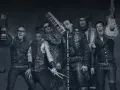 Rammstein-Bandmitglieder mit Instrumenten, schwarz-weiß.