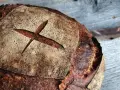 Ein frisch gebackenes Brot mit dunkler Kruste und einem Kreuzschnitt. So wird selbstgebackenes Brot dunkel: durch die Maillard-Reaktion beim Backen.