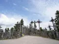 A vast mountain of crosses, with a statue of Jesus at its peak, stands under a cloudy sky.