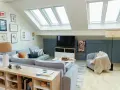 Soggiorno mansardato con divano grigio, camino, quadri alle pareti e lucernari. Idee su come dividere una mansarda in due stanze.