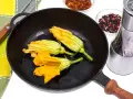 Fiori di zucca in padella, pronti per essere impanati e fritti. Accanto, spezie e sale per insaporire.