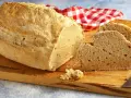 Pane casereccio con lievito istantaneo, tagliato su un tagliere di legno, con un tovagliolo a quadri rossi e bianchi.