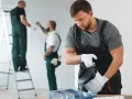 Trzech mężczyzn w ogrodniczkach maluje ściany. Czy w soboty można robić remont? Tak, jeśli masz ekipę!