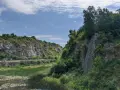 Kamieniołom z wodą i zielenią, skalne zbocza, niebo z chmurami.