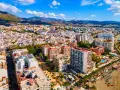 Widok z lotu ptaka na nadmorskie miasto Marbella, z górami w tle. Widać plażę, hotele i budynki mieszkalne.