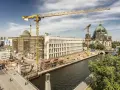 Baustelle am Berliner Dom, Kräne ragen in den Himmel. Ein neues Gebäude entsteht, während der Dom in seiner Pracht erstrahlt. Ein Blick auf das heutige Berlin, das sich ständig neu erfindet.