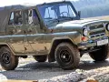 Zielony UAZ z plandeką, marka samochodu na u, pokonuje błotnisty teren.