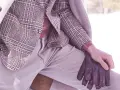 Un uomo indossa un elegante spezzato con giacca a quadri, maglione rosa e guanti in pelle marrone, pronto per l'inverno.