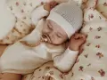 Śpiące dziecko w czapce i pajacyku z wełny merino. Czy wełna merino gryzie? Nie, jest miękka i delikatna dla skóry maluszka.