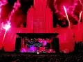 Ogromny budynek oświetlony na czerwono, fajerwerki i scena koncertowa. Tłum ludzi czeka na największy koncert na świecie.