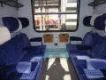 Wnętrze wagonu z niebieskimi siedzeniami w kratkę. Różne rodzaje wagonów oferują komfort podróży.
