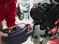 Osoba w czerwonej bluzie nalewa olej do silnika motocykla. Różne typy silników wymagają odpowiedniego smarowania.