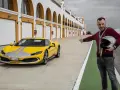 Żółte Ferrari 296 GTB z szarymi pasami na torze wyścigowym. Obok stoi mężczyzna z kaskiem, zapraszając do przejażdżki.