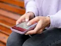 Dłonie kobiety obsługują smartfon, czując subtelne wibracje haptyczne przy każdym dotknięciu ekranu.