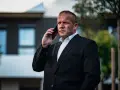 Krzysztof Bukowski, reżyser, w garniturze rozmawia przez telefon.